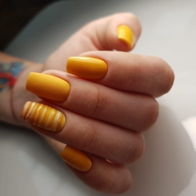Manicure com unhas amarelas e uma unha listrada de amarelo e branco