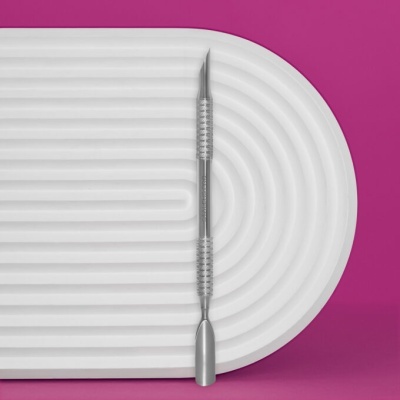 Dardo metálico prateado com corpo estriado numa base branca sobre fundo rosa