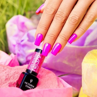 Frasco de verniz gel rosa Victoria Vynn com mão feminina e pó colorido