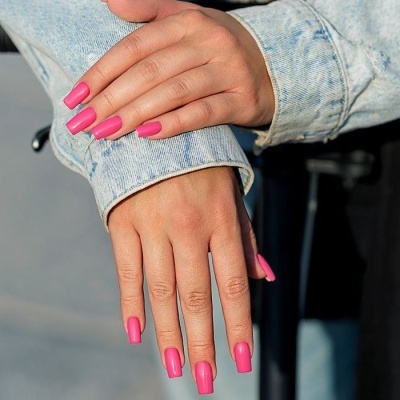 Mãos femininas com unhas rosas e casaco de ganga azul claro