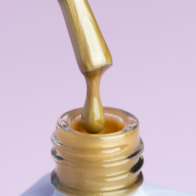 Pote de verniz para unhas aberto com pincel e verniz dourado metálico