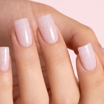 Unhas artificiais quadradas rosa claro com glitter prateado em mãos femininas
