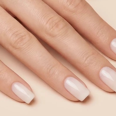 Mão feminina com unhas curtas quadradas cor nude brilhantes sobre fundo bege