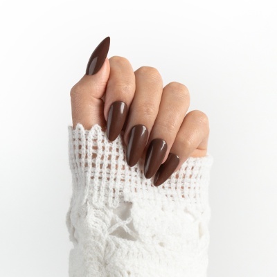 Mão com unhas castanhas brilhantes e tecido branco de malha