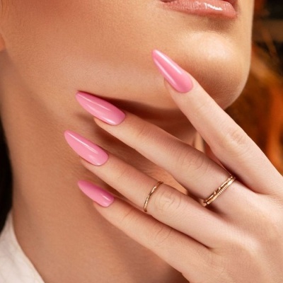 Mãos femininas com unhas rosa e anéis dourados