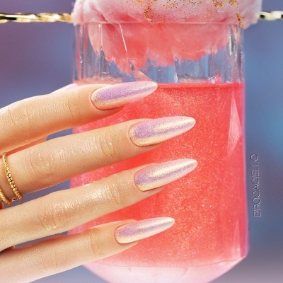 Mão com unhas verniz gel perolado rosado segurando copo com líquido rosa e algodão doce