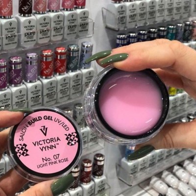 Frasco de gel para unhas Victoria Vynn LIGHT PINK ROSE em mãos femininas com unhas verdes