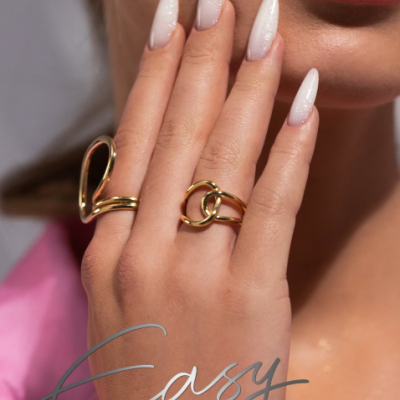 Mão com unhas brancas em gel e anéis dourados perto dos lábios com texto Easy FIBER GEL