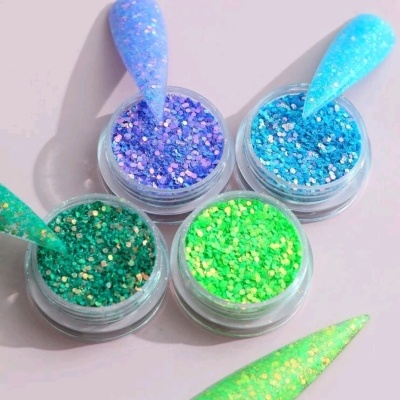 Frascos transparentes com purpurinas brilhantes azuis, verdes e lilás e amostras de ponto-de-unha
