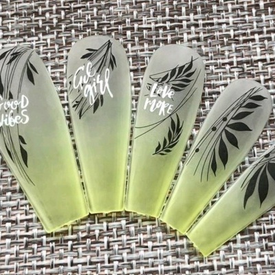 Unhas postiças verdes translúcidas com desenhos de folhas e texto em branco