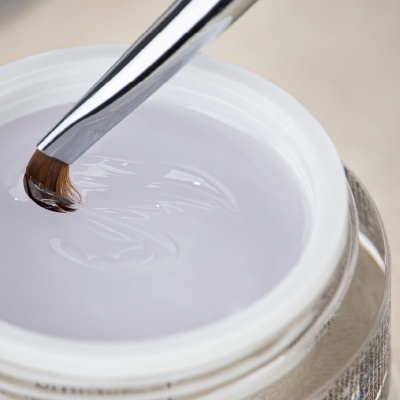 Frasco aberto de gel translúcido com pincel de unhas