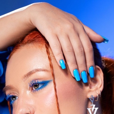 Pessoa com maquilhagem azul, cabelo ruivo e unhas azuis