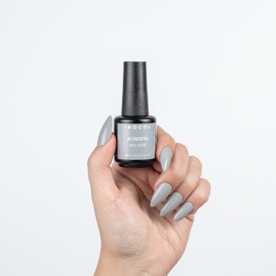 Frasco de verniz gel cinzento INOCOS na mão com unhas pintadas com a mesma cor