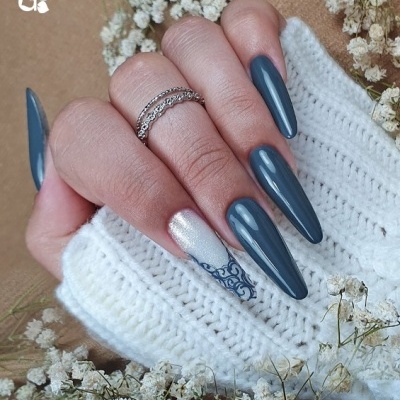 Mão com unhas longas pintadas de azul-acinzentado e decoradas com anéis e flores secas