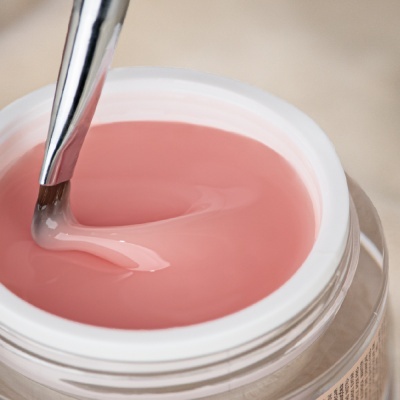 Pote aberto de gel rosa para unhas com pincel metálico