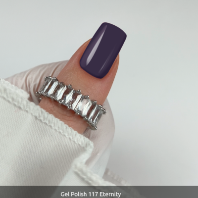 Anel prateado com pedras retangulares e unhas com verniz gel roxo escuro.