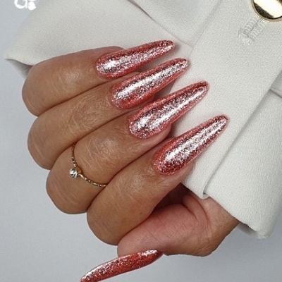Unhas compridas com verniz brilhante rosa-ouro com glitter