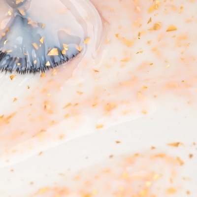 Pincel de maquilhagem com creme translúcido e partículas douradas