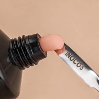 Aplicador metálico com creme salmão a sair de embalagem preta