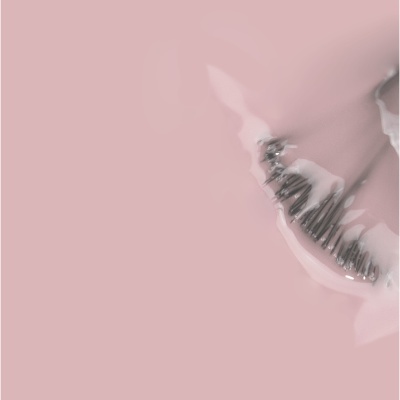 Pequenos ganchos metálicos pretos em fundo rosa com líquido branco translúcido