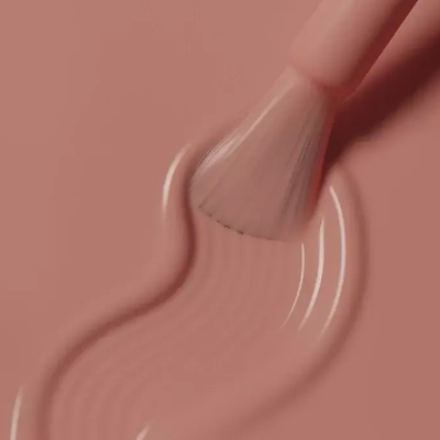 Pincel aplicando verniz de unha cor rosa nude