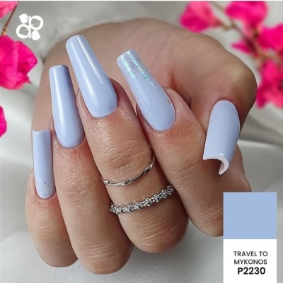 Unhas compridas azuis claras com detalhe holográfico e anéis prateados em mãos femininas