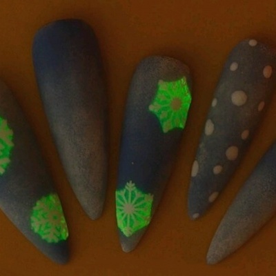 Unhas postiças azuis com padrões de flocos de neve e pontos brancos.