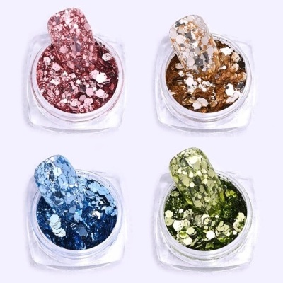 Quatro recipientes com glitter de cores rosa, dourado, azul e verde para unhas