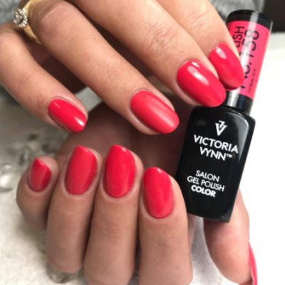 Mãos com unhas vermelhas brilhantes e frasco de verniz gel Victoria Vynn