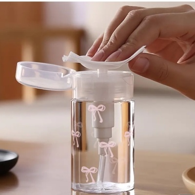 Frasco transparente decorado com laços cor-de-rosa e dispensador branco com tampa aberta.