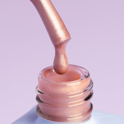 Frasco de verniz rosa claro com pincel aplicador e gotas de verniz