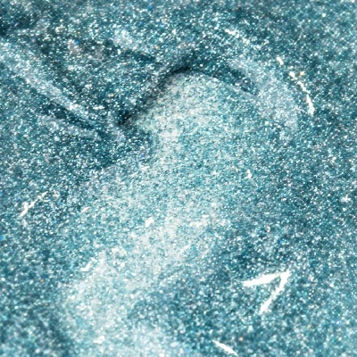 Close-up de líquido azul-turquesa brilhante com partículas metálicas prateadas