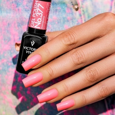 Mão com unhas rosa vibrante segurando frasco de verniz gel rosa e preto