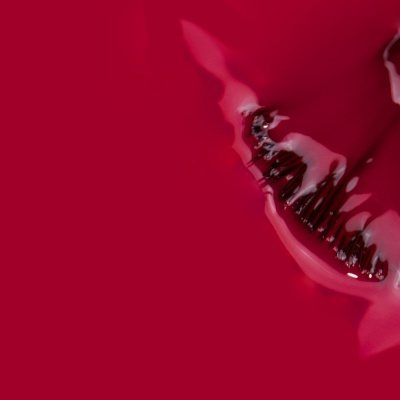 Escova dentada preta parcialmente embebida em líquido vermelho brilhante sobre fundo vermelho