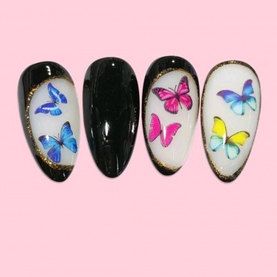 Unhas postiças decoradas com borboletas coloridas em fundo branco e preto
