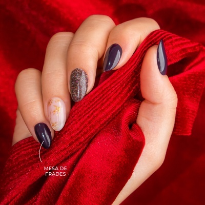 Mão com unhas coloridas segurando tecido vermelho aveludado