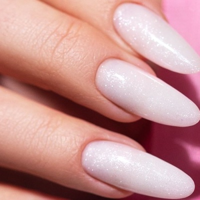 Unhas postiças brancas cintilantes em fundo rosa