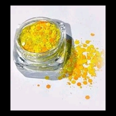 Frasco de vidro com purpurina amarela e dourada derramando