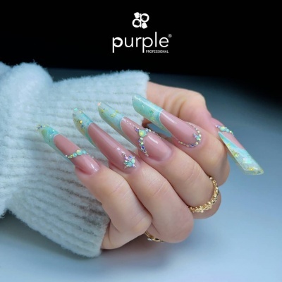 Unhas compridas decoradas com pedras e padrão azul na mão com anéis dourados