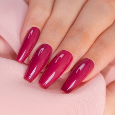 Unhas compridas pintadas de rosa escuro sobre tecido cor-de-rosa claro