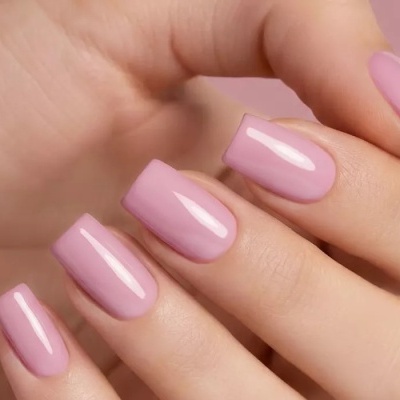 Unhas quadradas pintadas de verniz rosa claro em fundo rosa