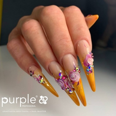 Unhas compridas com decoração amarela, flores cor de rosa e strass multicoloridos