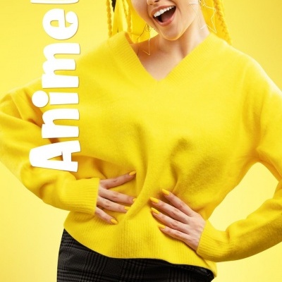 Mulher com suéter amarelo e saia xadrez preta num fundo amarelo com texto 'Anime like'