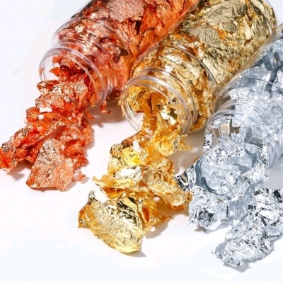 Folhas metálicas finas em cobre, dourado e prata derramadas de frascos transparentes