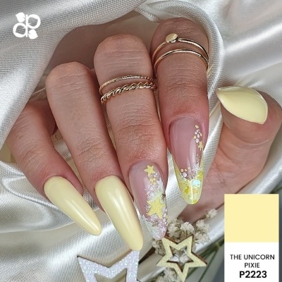 Unhas amarelas pastel e decoradas com estrelas e glitter
