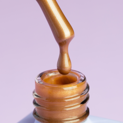 Frasco de verniz dourado com pincel e gota suspensa