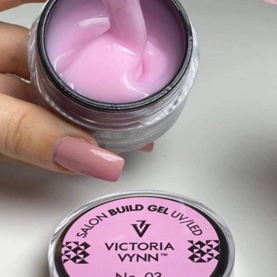 Gel de construção para unhas rosa suave em frasco aberto com tampa ao lado.