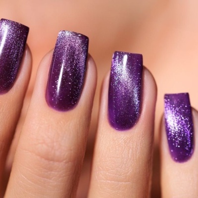 Unhas com verniz roxo brilhante e cintilante em quatro dedos