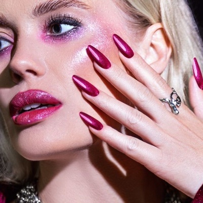 Mulher com unhas vermelhas metálicas e maquilhagem combinada