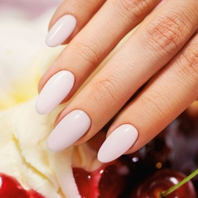 Unhas rosa pálido em formato oval com fundo de chantilly e cerejas